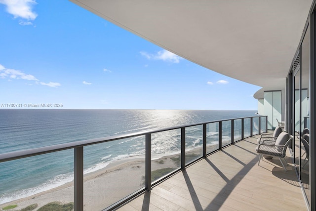 balcony with a water view and a view of the beach