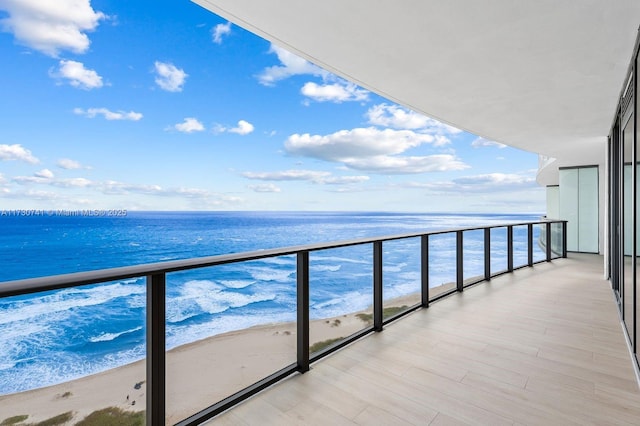 balcony with a water view and a view of the beach