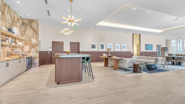 kitchen with a wainscoted wall, open shelves, a notable chandelier, and a center island