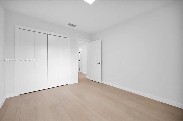 unfurnished bedroom with a closet and light wood-type flooring