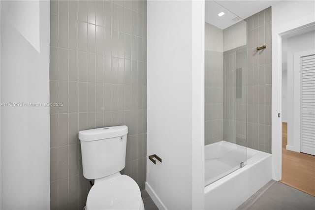 bathroom featuring tiled shower / bath combo, hardwood / wood-style flooring, tile walls, and toilet