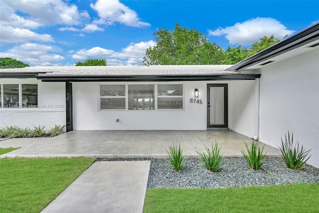 entrance to property with a patio and a lawn