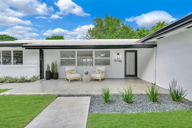 entrance to property featuring a patio area and a lawn