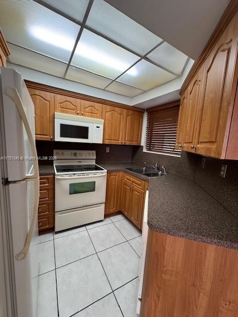 kitchen with light tile patterned flooring, white appliances, sink, and backsplash