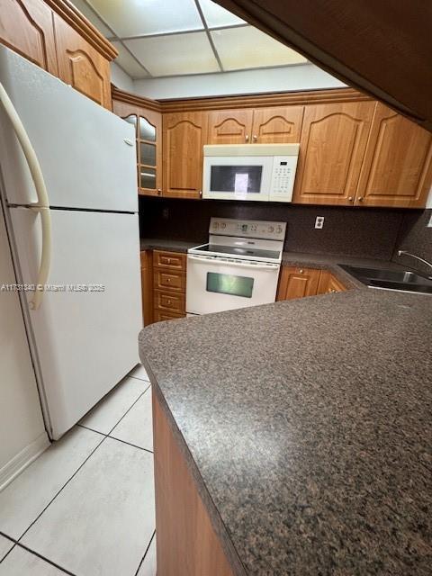 kitchen with sink, white appliances, light tile patterned floors, and decorative backsplash