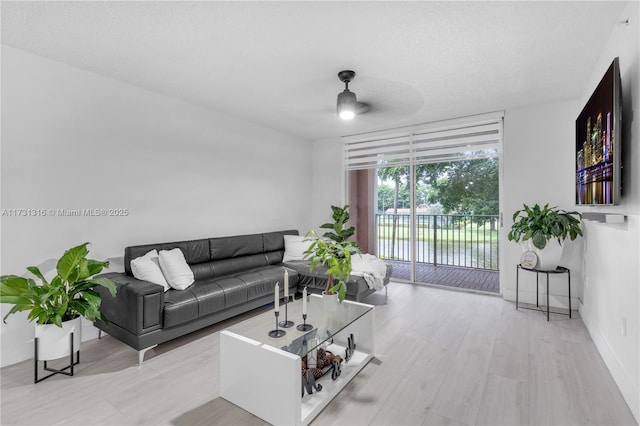 living area with ceiling fan, a textured ceiling, floor to ceiling windows, and wood finished floors