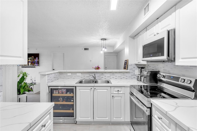 kitchen with pendant lighting, white cabinetry, sink, wine cooler, and stainless steel range with electric stovetop