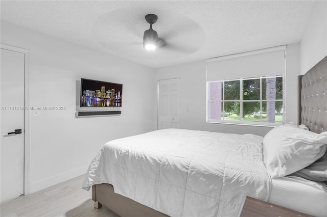 bedroom with ceiling fan, a textured ceiling, and light wood-type flooring