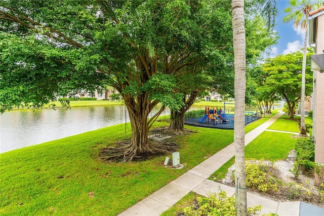 surrounding community featuring playground community, a lawn, and a water view