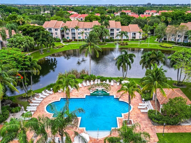 community pool with a patio area, a yard, a water view, and a residential view