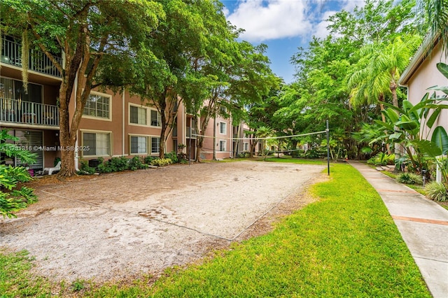 view of community featuring driveway, volleyball court, and a lawn