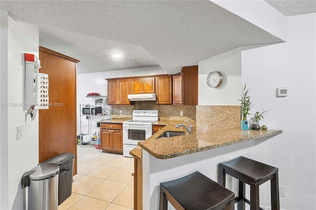 kitchen featuring sink, a kitchen breakfast bar, kitchen peninsula, and white range with electric stovetop