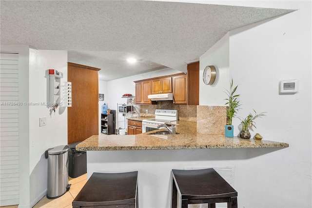 kitchen featuring a kitchen bar, kitchen peninsula, and backsplash