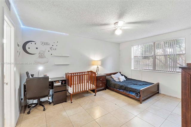 tiled bedroom with ceiling fan and a textured ceiling