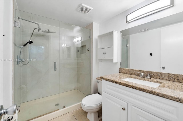 bathroom featuring tile patterned flooring, vanity, a shower with shower door, and toilet