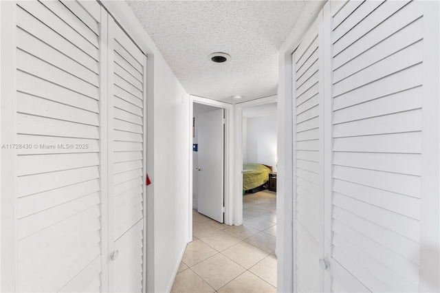 hallway with light tile patterned floors and a textured ceiling