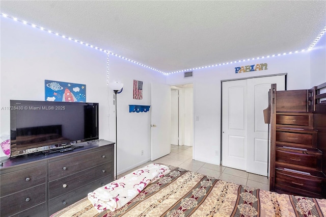 tiled bedroom with a closet and a textured ceiling