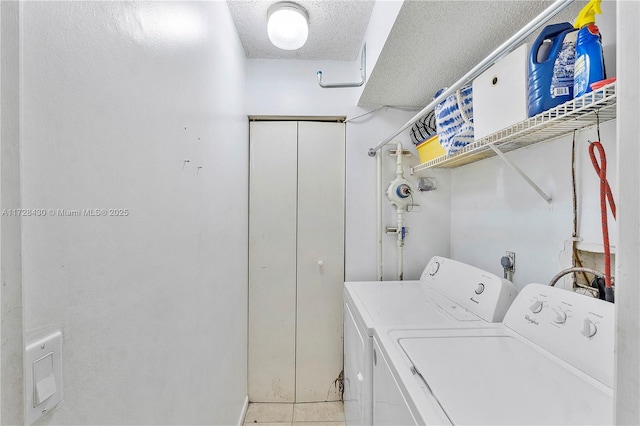 clothes washing area with light tile patterned flooring, a textured ceiling, and washer and clothes dryer