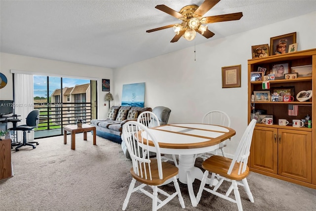 carpeted dining space with ceiling fan and a textured ceiling