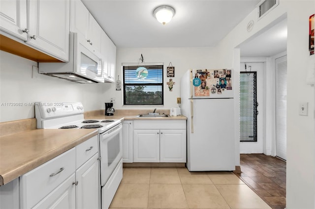 kitchen with light tile patterned flooring, white appliances, sink, and white cabinets