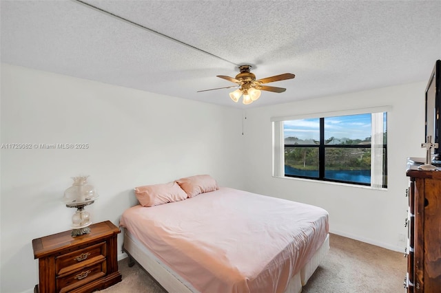 carpeted bedroom with ceiling fan and a textured ceiling