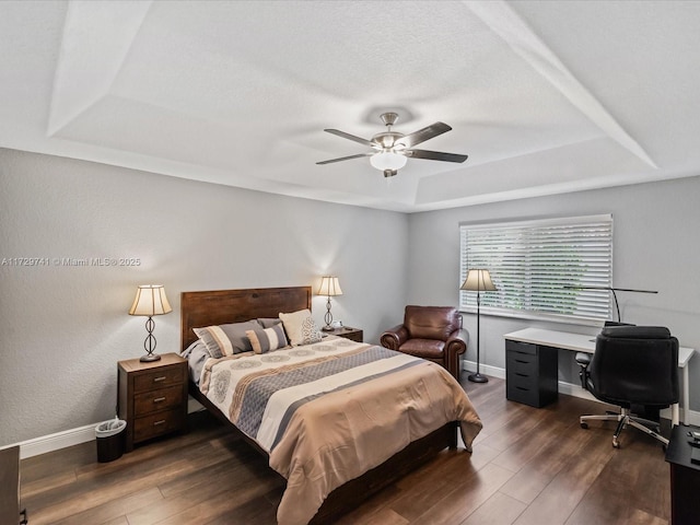 bedroom with dark hardwood / wood-style floors, a raised ceiling, and ceiling fan