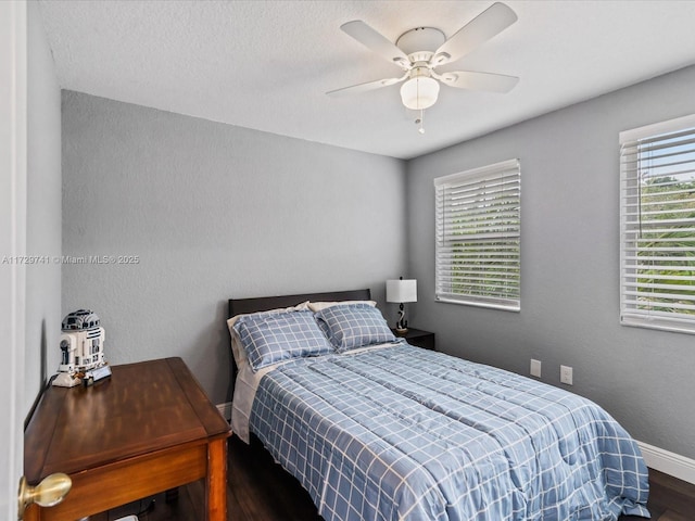 bedroom featuring multiple windows, dark wood-type flooring, and ceiling fan