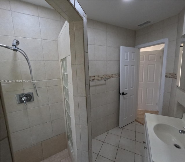 bathroom with walk in shower, vanity, tile patterned flooring, and tile walls