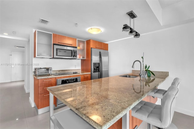 kitchen with sink, decorative light fixtures, a kitchen breakfast bar, kitchen peninsula, and stainless steel appliances