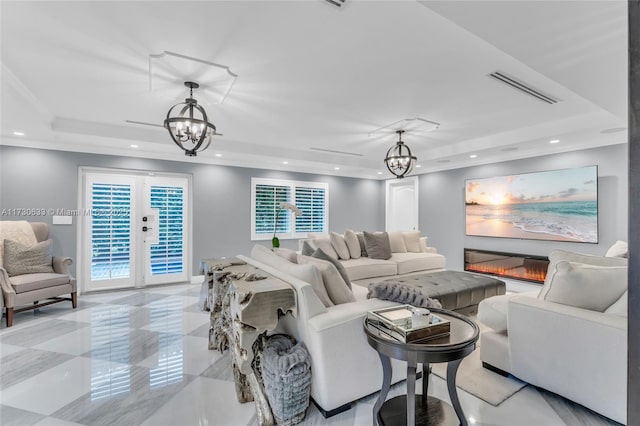 living room featuring french doors, a tray ceiling, and a notable chandelier