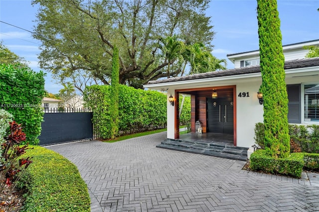 property entrance with a gate, fence, covered porch, and stucco siding