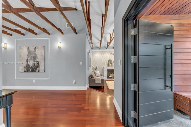 hall with visible vents, vaulted ceiling with beams, baseboards, and wood finished floors