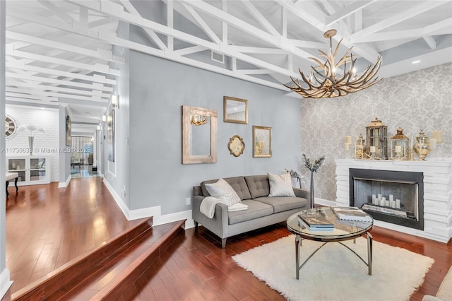 living room featuring baseboards, beamed ceiling, a fireplace, and wallpapered walls