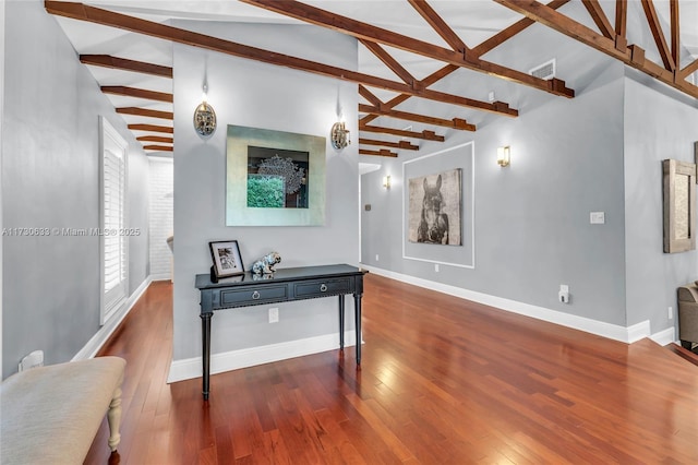 living area with vaulted ceiling with beams, baseboards, visible vents, and hardwood / wood-style floors