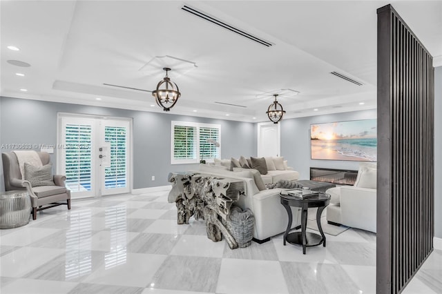 living area with french doors, visible vents, baseboards, a raised ceiling, and recessed lighting