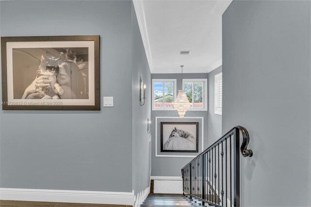 staircase featuring crown molding and a chandelier