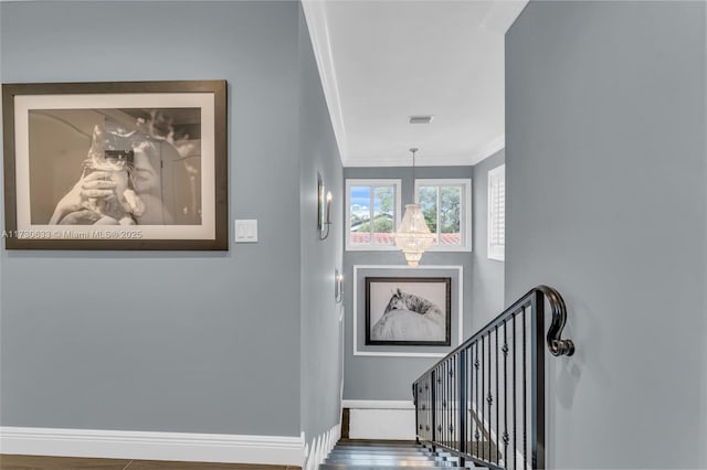 stairway featuring a chandelier, wood finished floors, visible vents, baseboards, and crown molding