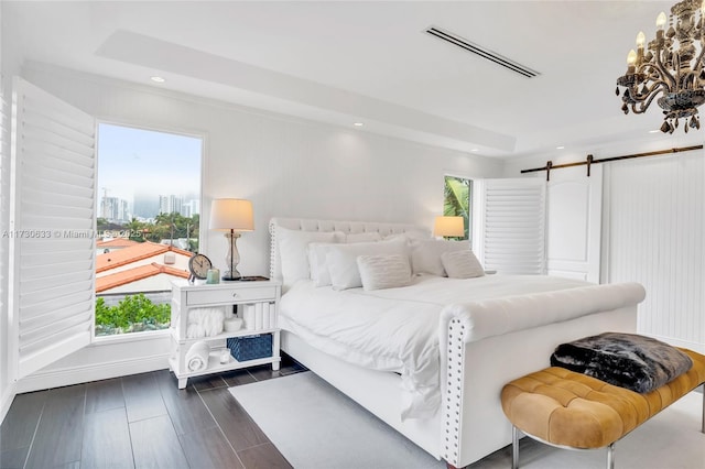 bedroom featuring a barn door, multiple windows, visible vents, and an inviting chandelier