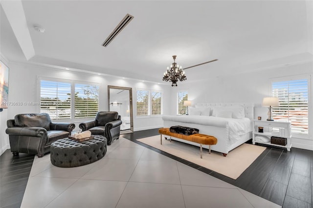 bedroom featuring multiple windows, a raised ceiling, dark tile patterned floors, and an inviting chandelier