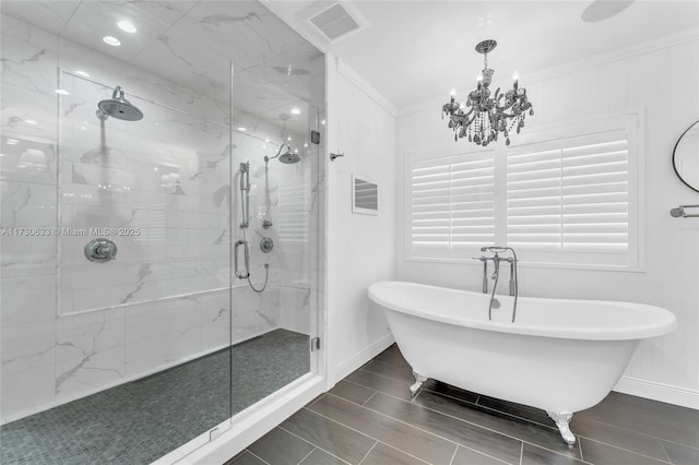 bathroom featuring a marble finish shower, visible vents, a freestanding bath, ornamental molding, and baseboards