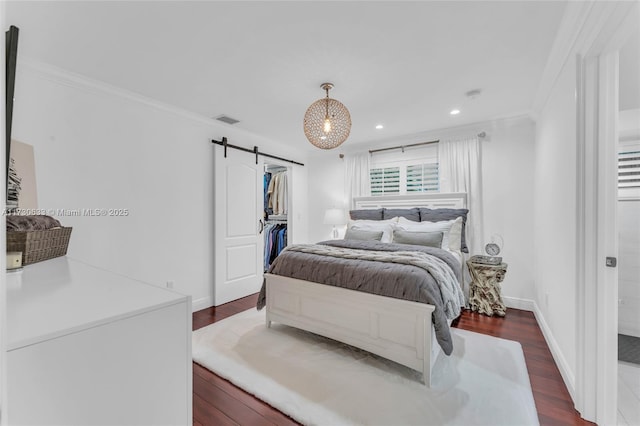 bedroom with a barn door, visible vents, baseboards, dark wood-style floors, and crown molding