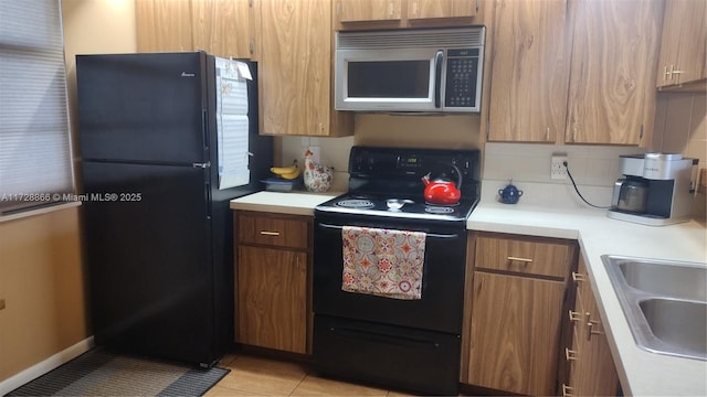 kitchen with light tile patterned flooring, sink, backsplash, and black appliances