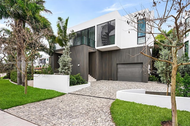 contemporary house featuring a garage, a balcony, and a front lawn