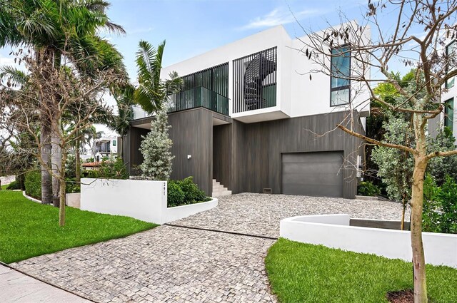 modern home with an attached garage, a front lawn, and a balcony