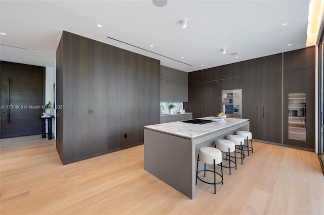 291 Palm Ave, Miami Beach, FL 33139 - kitchen with modern cabinets, a kitchen bar, a center island, light wood-type flooring, and black electric cooktop