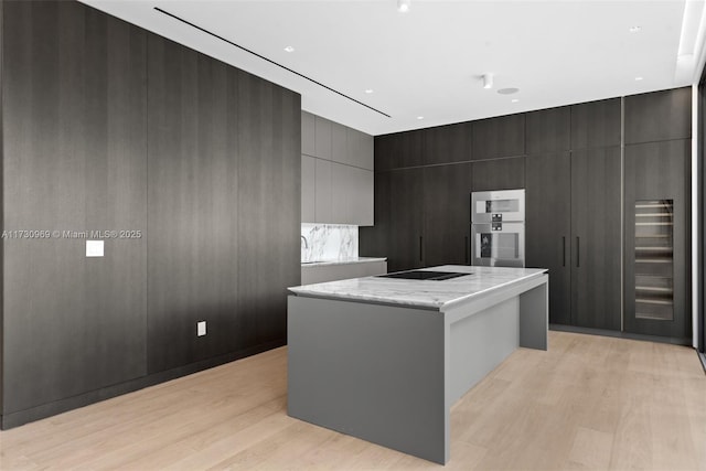 kitchen with a center island, black electric cooktop, and light hardwood / wood-style flooring