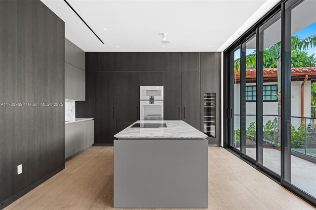 kitchen featuring black electric cooktop, a center island, light hardwood / wood-style floors, and a wealth of natural light