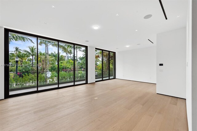 spare room with floor to ceiling windows and light hardwood / wood-style floors