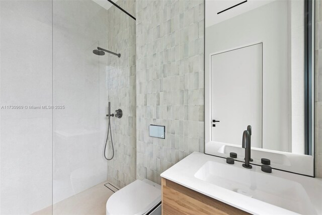 bathroom with vanity, a tile shower, and toilet