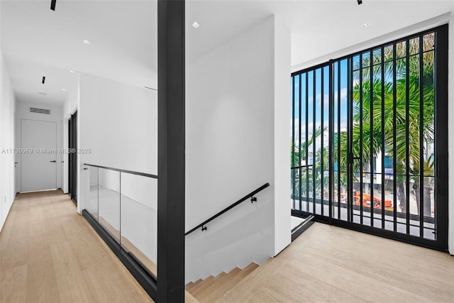 hallway with plenty of natural light, floor to ceiling windows, and light wood-type flooring